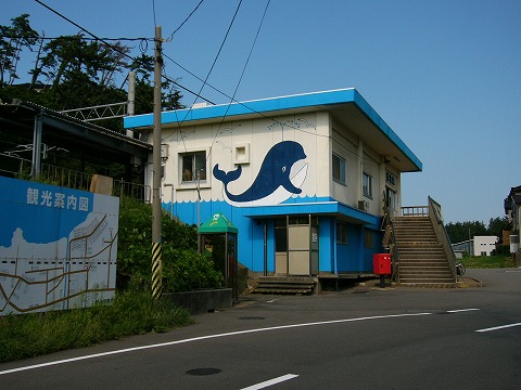 下半分は水色に塗られ、濃い青の鯨の書かれた直方体の駅舎