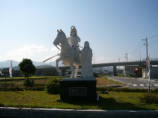 二人物の白い石像。左は馬に乗った武士で、右は女性。