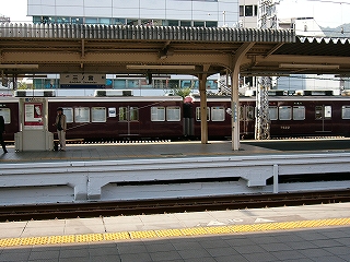 向こうのホームの向こうを阪急電車が通っている。