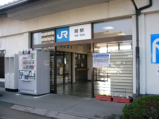 横向きの桟が入った幅広いひきどの駅舎入口。引き戸と天井の間の部分に「JR 関駅」と掛かれた看板が取り付けられている。