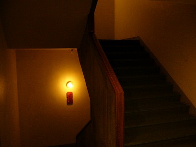 暗い中、明かりがぽつんと灯るエレベータ横の階段