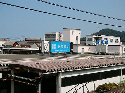 平屋の駅舎屋根の上に水色の電照式看板。