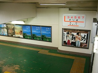 左への曲がり角。壁にはポスターが貼られ、地面は緑色。