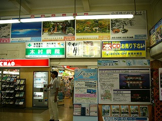 天井のすぐ下に四季折々の敦賀市の観光名所の風景、その下に3つの電照式広告、その下の一部にガラス扉待合室への入り口、右手にはJRのカードやきっぷの宣伝の大きなパネルが少し手前に張り出している。