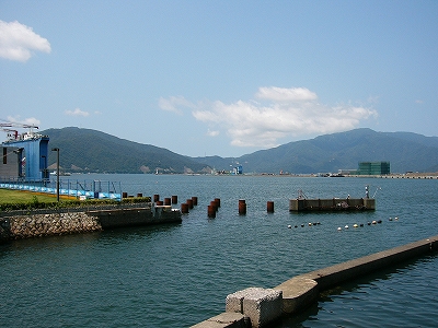 古いコンクリートの河口近くから港を。しかし少し遠くにはすぐ敦賀半島の大きな山塊が控えている。