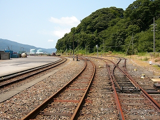 踏切から線路を。左には金ヶ崎の山。右にはコンテナ取り扱いの広場。