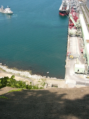 土を固めたようなでこぼこの斜面。下には港の隅の水辺へが見えている。