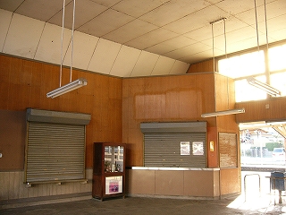 鼠色のシヤッターで閉ざされた窓口２つ。右手の窓口は出札口で、駅舎内の隅に、斜めにしつらえられている。