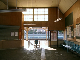 明るい木目の板が張られた壁の駅舎内。改札口上部には大きな明り取りの窓がある。