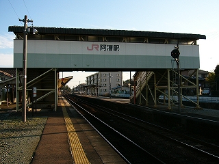 壁の下部分は灰緑、それより上の部分は白色の壁を持つ跨線橋。壁の白々の部分には「JR阿漕駅」と書かれている。