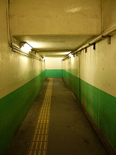 下は緑色、上はクリーム色の壁の地下道。