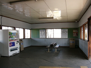 コンクリートの床、白い壁と白い天井の駅舎内。