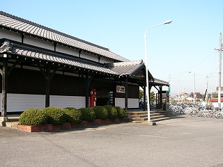 黒い柱で支えられた屋根瓦の回廊を持つ駅舎。
