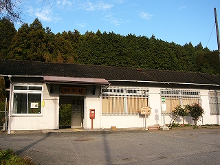左に窓が一つ、その次に駅舎の入口、そして桟の入った駅務室の窓が2つ並ぶ、白い壁で黒い屋根を持つ平屋の駅舎。