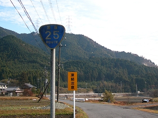 国道25号を表示する青色の看板と道路に屹立する高い山。