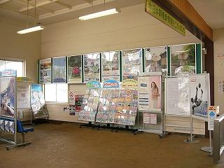 壁には大型のポスターが貼られ、壁の前にはパンフレット棚が置かれた光景。