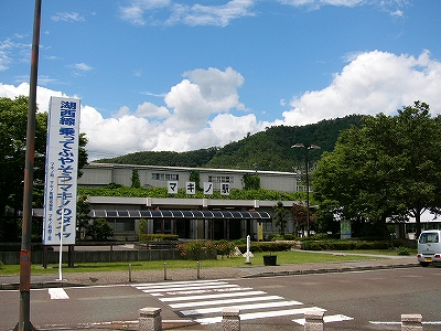 左手に白地に青字で書かれた琵琶湖環状線の宣伝塔、右手に駅舎と駅前。
