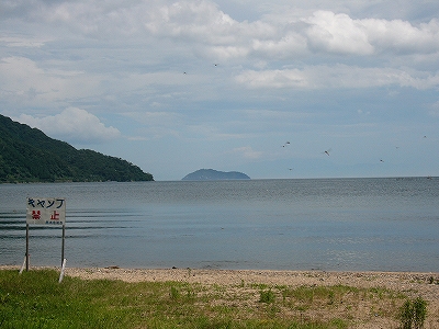 薄い漣の湖面。左手奥に緑の茂る海津大崎が突き出し、写真の真中あたりにひょうたんの断面のような竹生島。