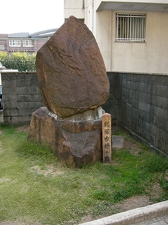 石の上にでっかい石の載ったもの。石はこげ茶色に変色している。石のある小さな四角い敷地は芝生になっている。