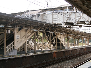 跨線橋から二股におりた階段。両階段の間には複雑にクリーム色の鉄骨が組まれている。