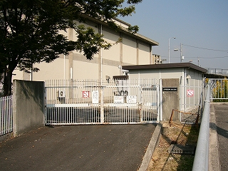 門は白い柵で、そのすぐ向こうに建物の壁。