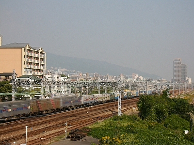 左斜めに横切る太い東海道本線。ずっと向こうの方に緩やかな斜面にできた街。