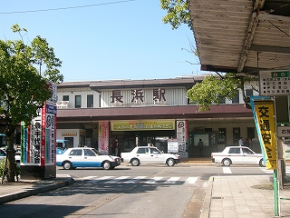 白と小豆色を基調とした二階建ての駅舎。入口上部に大きく「長浜駅」と小豆色の文字で表示されている。