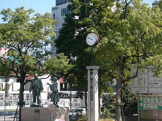 小さめの銅像とポールで立っている時計塔。