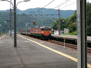 窓枠を含む太い幅は橙色で上下は緑の車両が前後に一つずつ、真中二両はベージュ系統の列車。