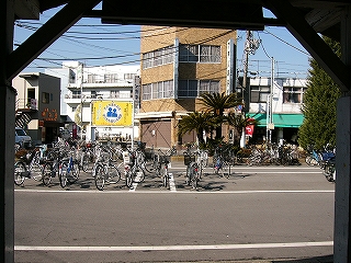 薄茶色のビル、緑色のビニールの軒を持つ店、ロータリーの自転車。