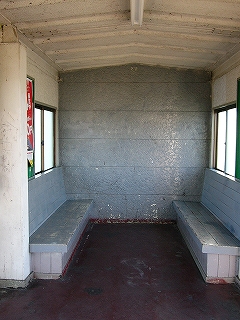 両脇に据付のベンチのある駅舎内。壁とベンチはねずみに色に塗られている。