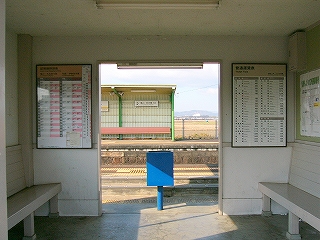 両脇に木製の白い椅子が据え付けられた駅舎内。床はつるつるしたコンクリートのまま。