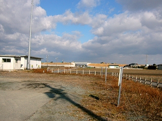 牧場で使われるような柵がめぐらされた駅前。柵の向こうは広がる田。