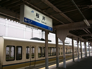上屋から吊るされた桜井駅の電照式駅名標と221系のボディー。