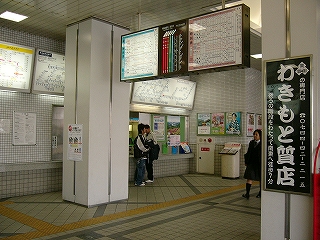 四角い柱の間から見える券売機。柱の間には時刻表と時計がセットで吊られている。