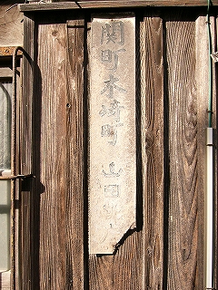 完全に色落ちしてはげてしまった細長いホーロー板に古めかしい字で「関町木崎町山田靴店」と書かれてある。