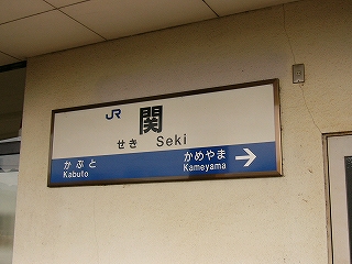 駅舎の白いコンクリートの壁に取り付けられた駅名標。