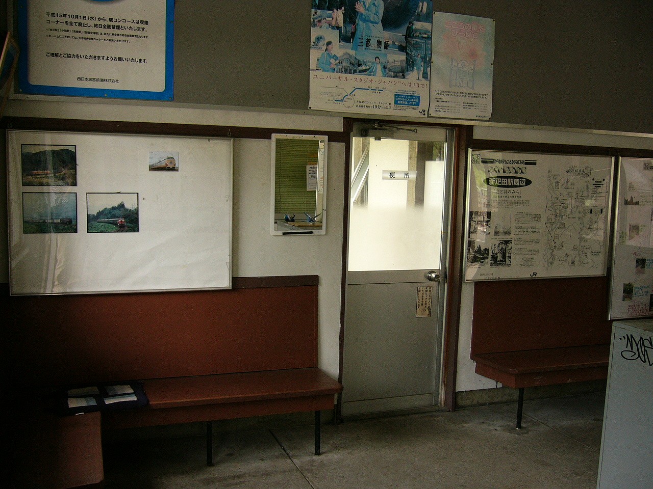 茶色の椅子に白壁、掲示物、窓ガラスつきの灰色のドア