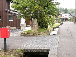 角型の赤いポストと石碑と水路