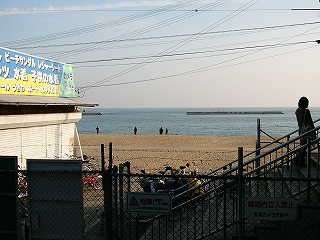 銀ねずみ色のフェンスの向こうは砂浜と海。