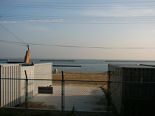 フェンスと白い倉庫と砂浜と海。