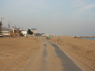 砂浜の中に一条に伸びるアスファルトの道。