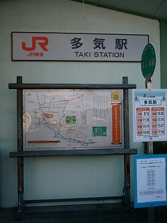 上部に横長の駅名表示板。その下に案内図が立ち、右手に小さなバス停。