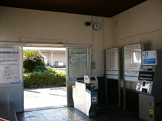 サッシの引き戸の出入口と右手に改札機群、上方にアナログ時計。