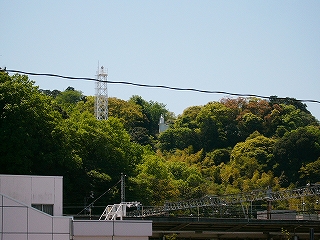 燃え上がる緑の中に立つ高い塔と、灯台のような建物。