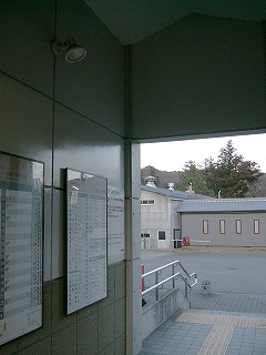 駅舎内かせ外へ出る短い通路。左の壁に時刻表と運賃表が掲げられている。