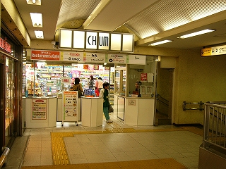 正面にお店と直結する小さな有人改札口。改札口の右にブースに駅員が座っている。
