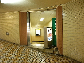 地下道の壁の左側に間口が開き、その前に「味の名食街」と書かれた電照式看板が置かれている。