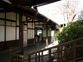 駅舎の漆喰と木の壁と、階段の木製の手すりと緑の植え込み。
