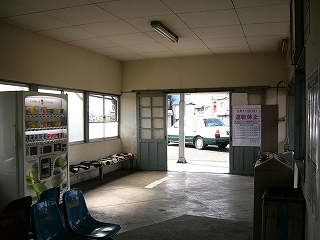 自販機、椅子、ゴミ箱のある駅舎内。